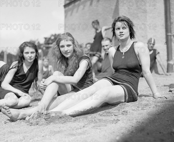 Three young women or teen girls sitting on a beach ca. between 1909 and 1932