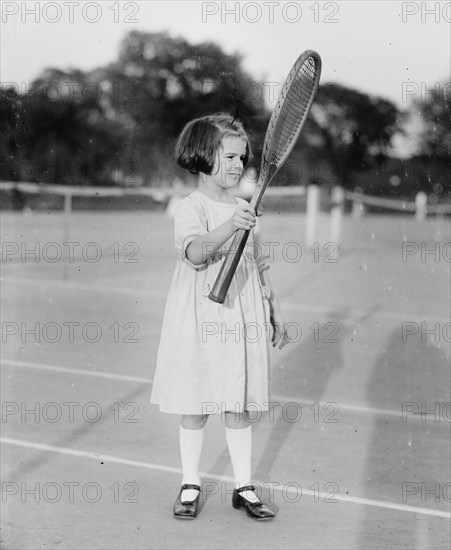 Peggy Baker on tennis court, holding a tennis racquet  ca.  between 1918 and 1920