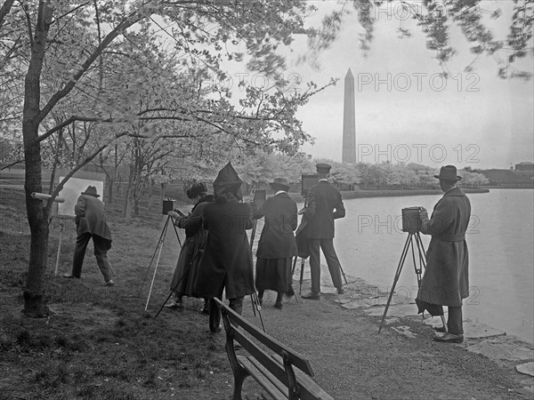 Photographers taking a photo of a man painting on a canvas, the Washington Monument in the background ca. [between 1909 and 1940]