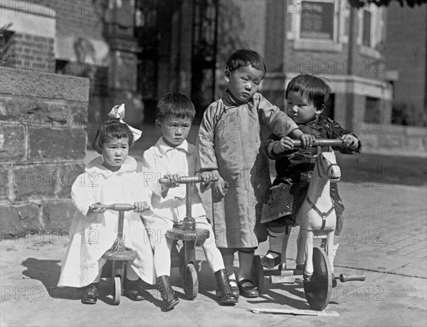 Four children, possibly Chinese, with small tricycles ca. 1909