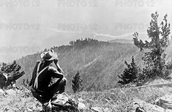 Cabinet National Forest, Montana. Man looking out over Clarks Fork Valley into Bitterroot Range from Mt. Silcox Lookout ca. 1909