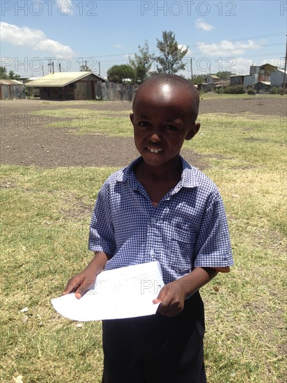 A young student holds a poem he wrote to welcome the USAID team for a groundbreaking in Kibera  ca. 27 February 2014