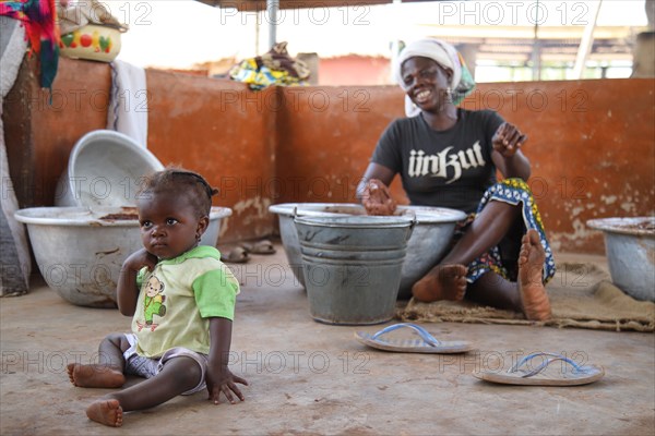 A West African village woman in northern Ghana works with her child in close proximity ca. 20 February 2018