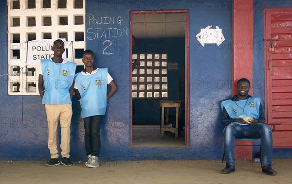 Three poll workers stand outside a polling station in Sierra Leone which marked a peaceful transfer of power from a ruling party to the opposition when Julius Maada Bio of the Sierra Leone People's Party assumed the presidency followinga run-off election