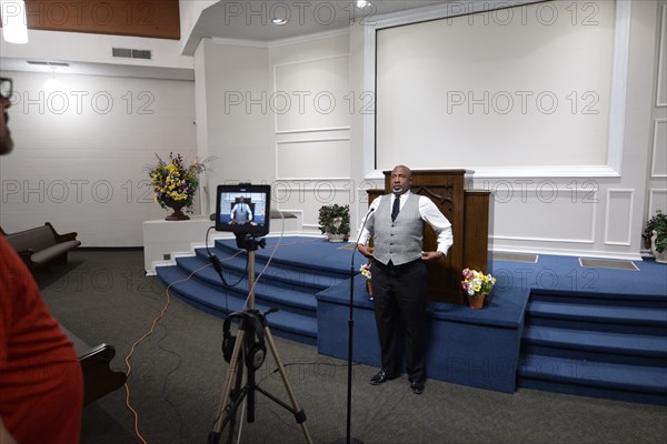 During the Covid-19 pandemic, some churches chose to record sermons to play on their websites and through streaming services to replace in person worship. Here, a technician records a minister as he preaches to the camera.