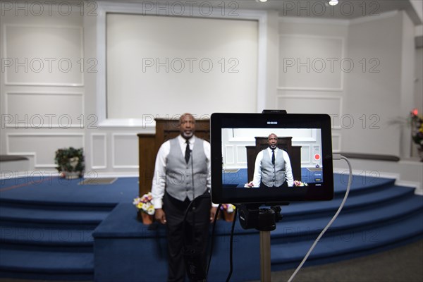 During the Covid-19 pandemic, some churches chose to record sermons to play on their websites and through streaming services to replace in person worship. Here, a technician records a minister as he preaches to the camera.