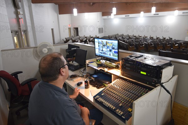 During the Covid-19 pandemic, some churches chose to record sermons to play on their websites and through streaming services to replace in person worship. Here, a deacon of the church looks on as a minister has his Sunday morning sermon recorded.