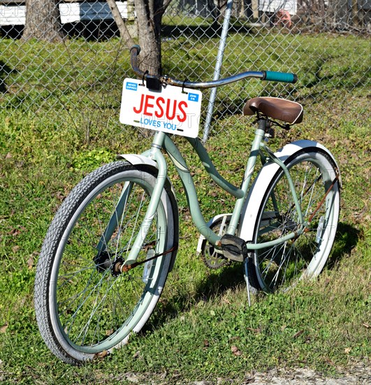 A bicycle with a JESUS license plate sitting in the front yard of a home in a small Texas town