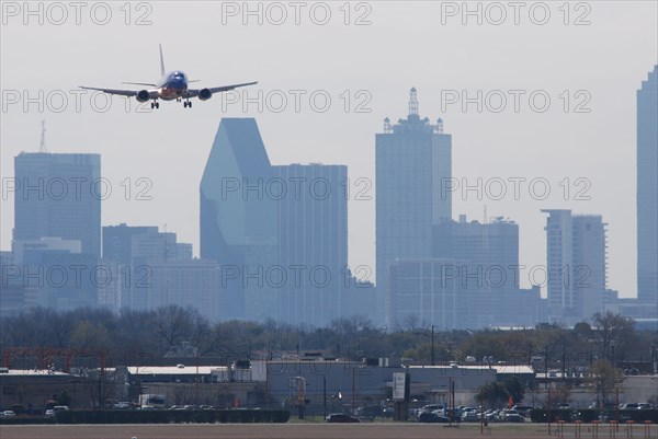 A Southwest Airlines plane landing at Love Field in Dallas, TX; Downtown Dallas in the background (ca. 2010, note the old color scheme)