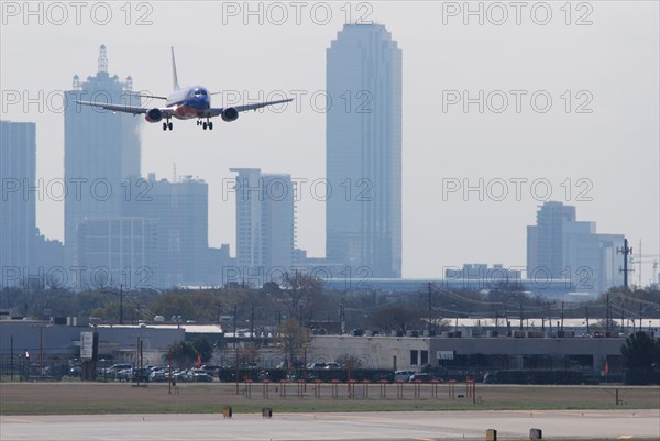 A Southwest Airlines plane landing at Love Field in Dallas, TX; Downtown Dallas in the background (ca. 2010, note the old color scheme)