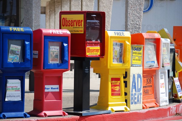 Newspaper stands offering free advertising papers litter a parking lot