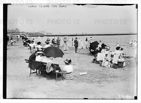 Over-dressed revelers relax on the beach at Coney Island