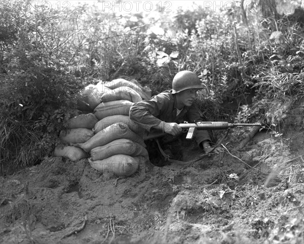 Carrying his carbine in readiness for action