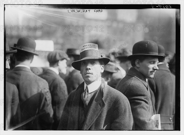 Man wearing hat with card reading 'Bread or revolution'