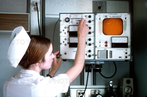 A nurse checks a monitor in a patient's room.