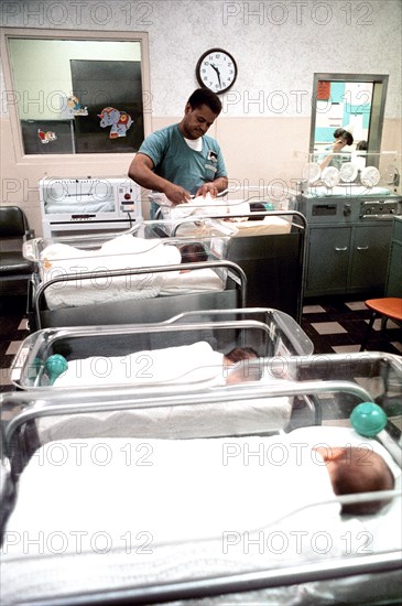 Woman tending to a newborn baby in the infant ward at Womack Army Hospital.