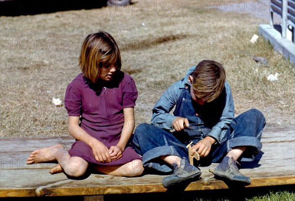 Boy building a model airplane [as girl watches]