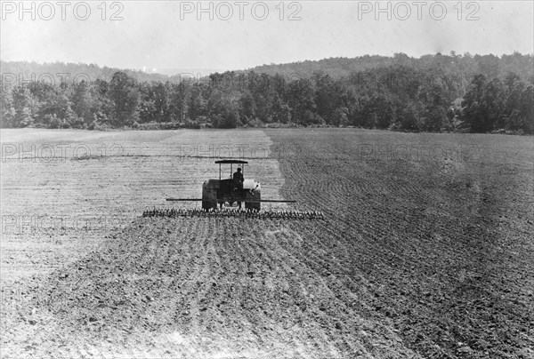 Farmer on a tractor working in a field with disc implement