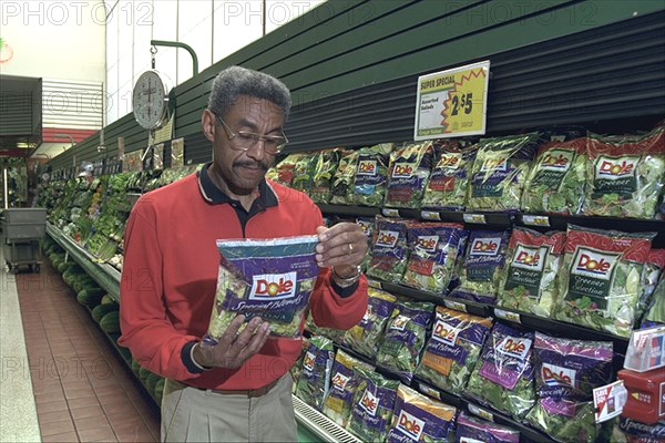 Shopper Looks Over Packaged Lettuce