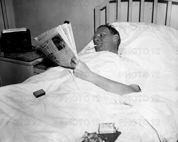 Man in hospital bed smoking a cigarette