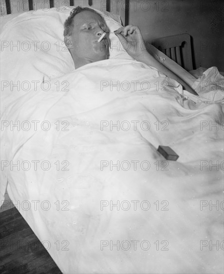 Man in hospital bed smoking a cigarette