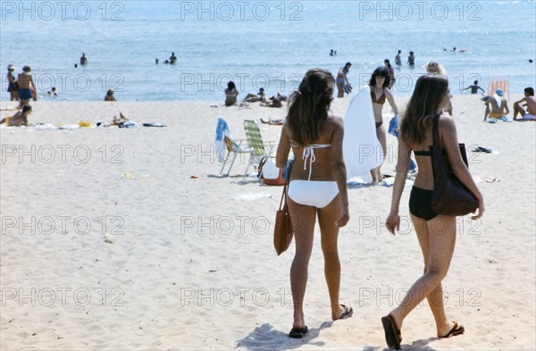 Two beautiful women in bikinis walking on a Florida beach