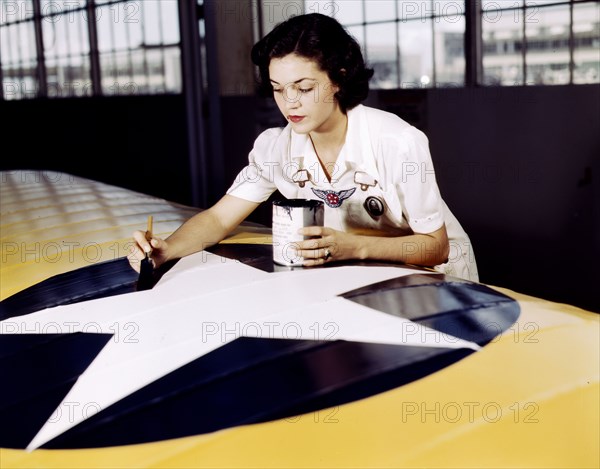 Woman defense industry worker paints the American insignia