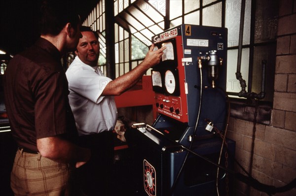 Worker shows a man that his car had passed an emissions test