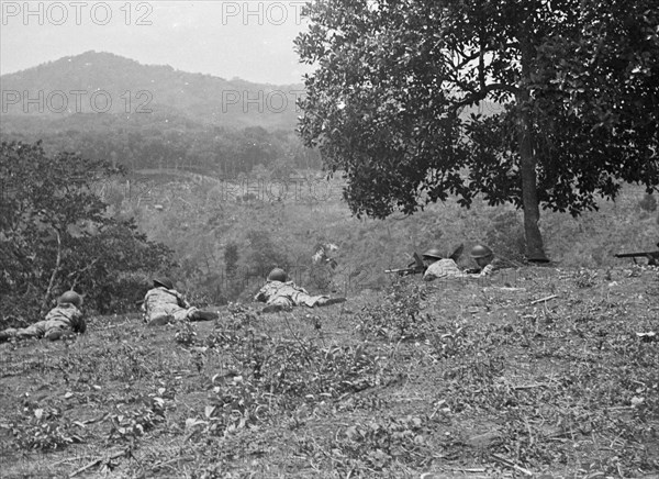 Soldiers lie on the ground in position and overlook a valley in Bandung, Indonesia, Dutch East Indies ca. 1946