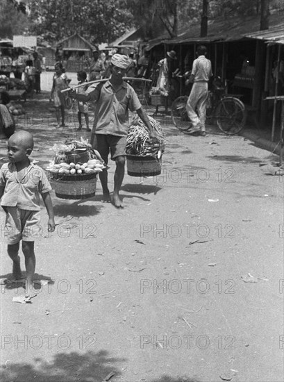 Vegetable seller with baskets on yoke; Date 1947; Location Indonesia, Dutch East Indies