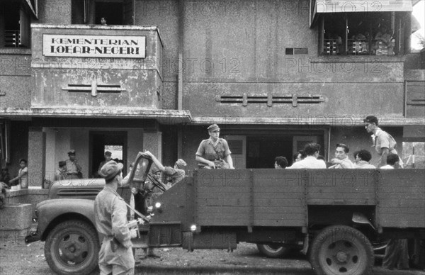 Prisoners (Republican officials) taken away by soldiers and Military Police. On the building the sign 'Kementerian Loear-Negeri' [Ministry of Foreign Affairs]; Date July 20, 1947; Location Batavia, Indonesia, Jakarta, Dutch East Indies