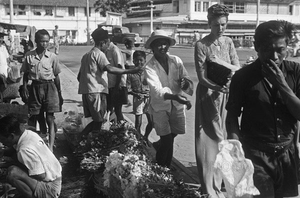 1940s Indonesia - Street scenes. A Dutch woman buys flowers from a florist - 24 August 1948