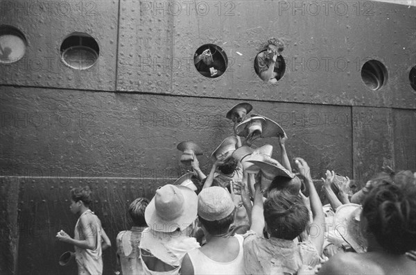 Soldiers throw cigarettes from the portholes for the children on the quay in Jakarta Indonesia ca. 1946