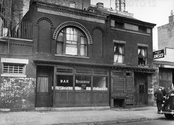 Two story bar and restaurant, small house and at far right, a junk shop. West 18th Street, Nos. 461-463, Manhattan ca. 1938