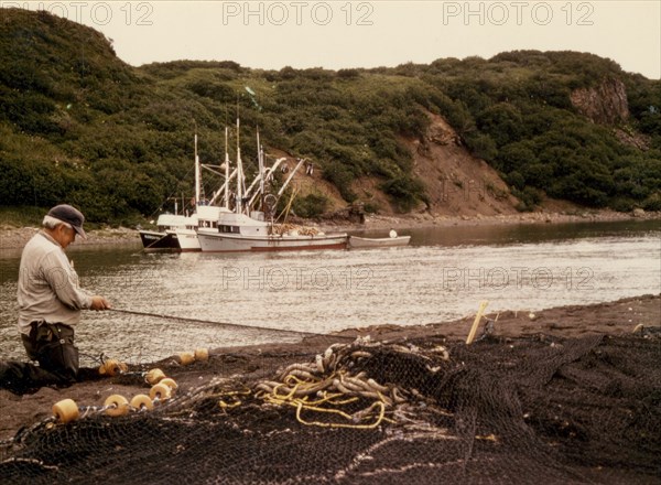 Salmon fisherman repairing nets. Boats are in Aniakchak River 7/17/1973