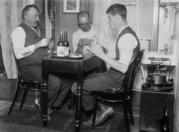 Men playing cards next to a primus stove in a home in Broad Channel, Queens ca. 1910-1915