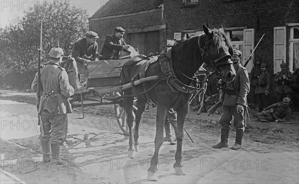 Belgian men in a horse-drawn cart, showing a pass to German soldiers during World War I ca. 1914-1915