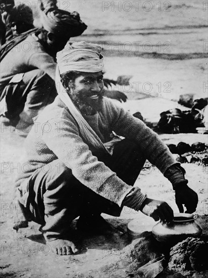 Indian soldier cooking outside over an open fire in France during World War I ca. 1914-1915