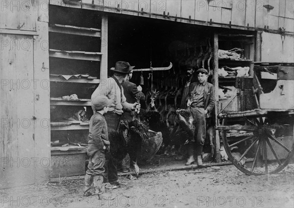 A father and a son buy their Thanksgiving turkey from a local vendor ca. 1910-1915