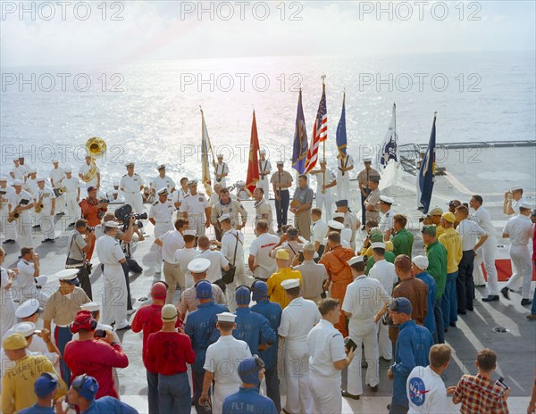 (21 July 1966) The crew of the Gemini-10 spaceflight, astronaut John W. Young (left), command pilot, and Michael Collins, pilot, talk on live radio and television during welcome aboard ceremonies on the deck of the USS Guadalcanal.