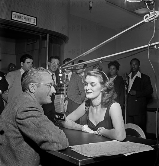 Tommy Dorsey (left) interviews the English pigeon, Beryl Davis, for his first disc jockey stint, with such names as Georgie Auld, Ray McKinley, Mary Lou Williams, Josh White and others visible in the background