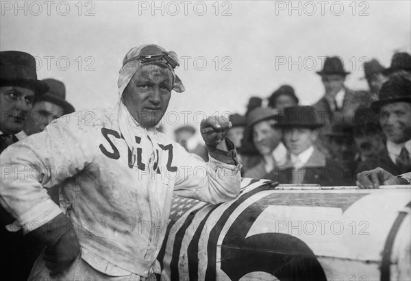 Racecar driver Gil Andersen standing next to his Stutz White Squadron racer ca. 1915