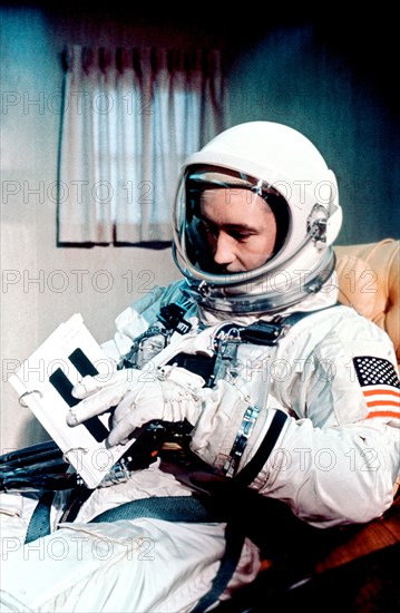 (3 June 1965) Astronaut James A. McDivitt, Gemini-4 command pilot, is shown in full spacesuit in the suit trailer prior to launch. He is reviewing a crew procedures flip book.
