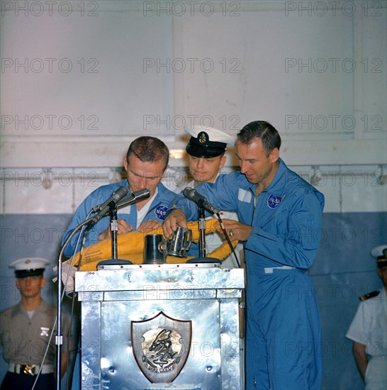 (18 Dec. 1965) Astronauts Frank Borman (left), Gemini-7 command pilot, and James A. Lovell Jr., pilot, take time out during their welcoming ceremonies aboard the aircraft carrier USS Wasp to autograph a life preserver.