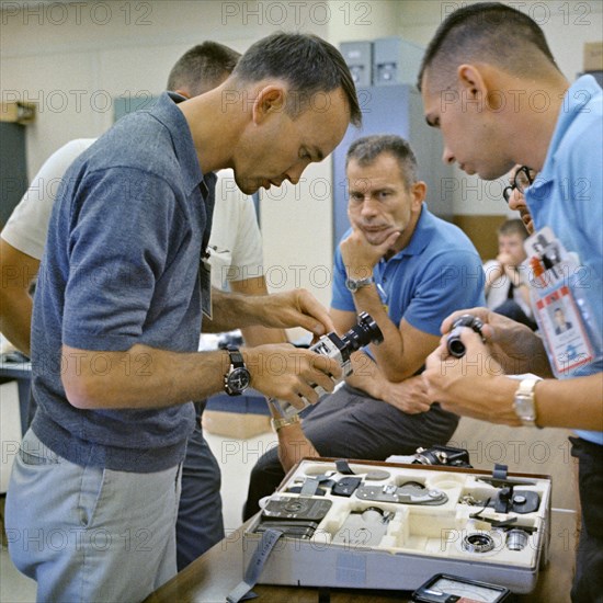 (18 July 1966) Astronaut Michael Collins (left), Gemini-10 prime crew pilot, inspects a camera during prelaunch activity at Cape Kennedy, Florida.