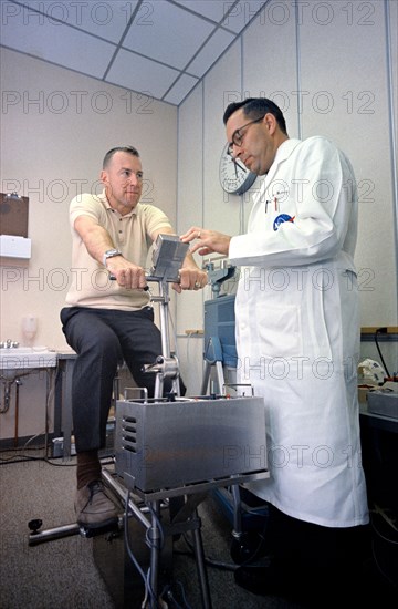 (2 Dec. 1965) Dr. Charles A. Berry checks astronaut James A. Lovell Jr., Gemini-7 prime crew pilot, following a workout on an exercise machine.