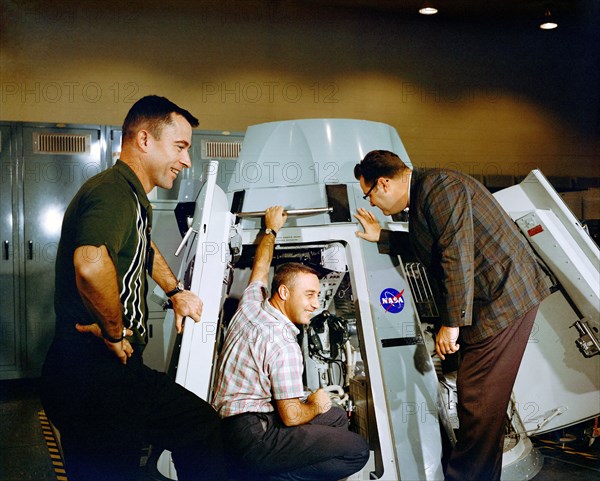 (19 Nov. 1964) Astronauts Virgil I. Grissom (center) and John W. Young (left), prime crew for the Gemini-Titan 3 mission, are shown inspecting the inside of Gemini spacecraft at the Mission Control Center at Cape Kennedy