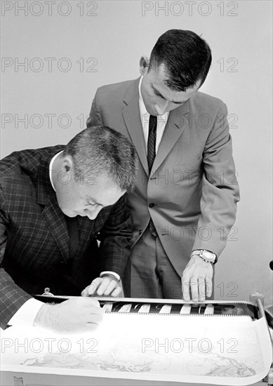 (25 March 1965) Gemini-Titan 3 astronauts Virgil I. Grissom (left) and John W. Young examine some of the negatives of photographs taken on their three-orbit flight on March 23, 1965.