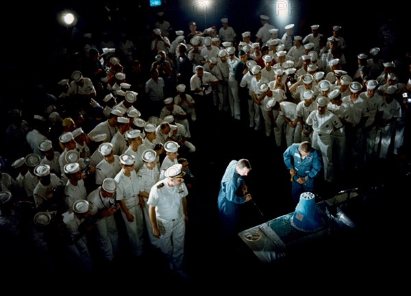 (18 Dec. 1965) Astronauts James A. Lovell Jr. (left), Gemini-7 pilot, and Frank Borman (right), command pilot, slice into a huge cake which was part of their warm welcome after arriving aboard the aircraft carrier USS Wasp.