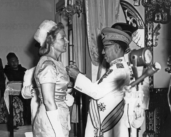 His Highness the Sultan pinning the Sultan Omar Ali Saifuddin medal on Mrs. M. E. Lloyd-Dolbey ca. 1960